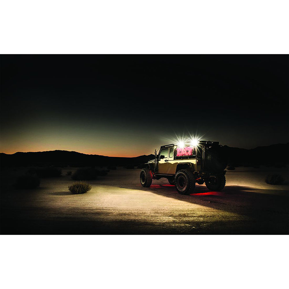 Jeep with bright LED lights and red underglow in desert at dusk, showcasing off-road lighting setup