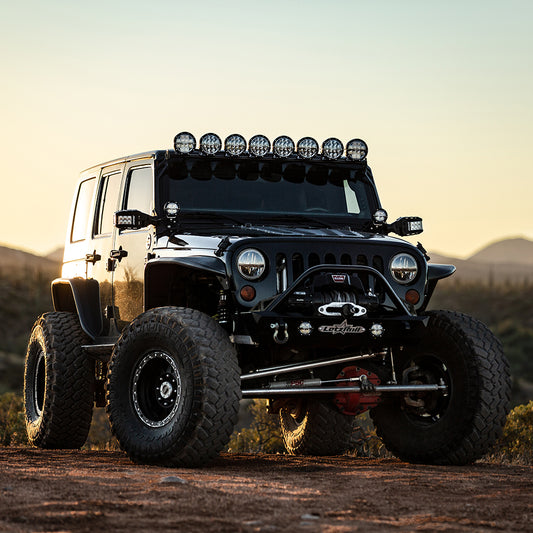 Custom lifted Jeep with off-road lights, winch, and large tires for rugged terrain adventures.