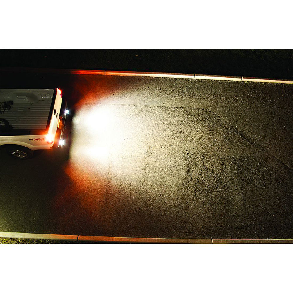 White truck with bright LED backup lights illuminating pavement at night, showcasing enhanced visibility and safety.