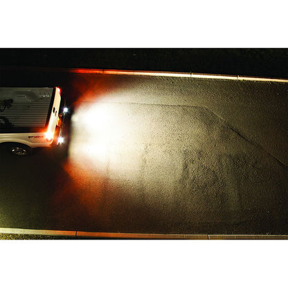 White truck with bright LED backup lights illuminating pavement at night, showcasing enhanced visibility and safety.