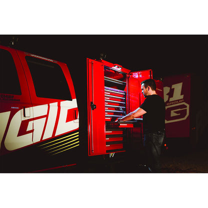 Mechanic accessing tools in red mobile workshop van with illuminated storage drawers