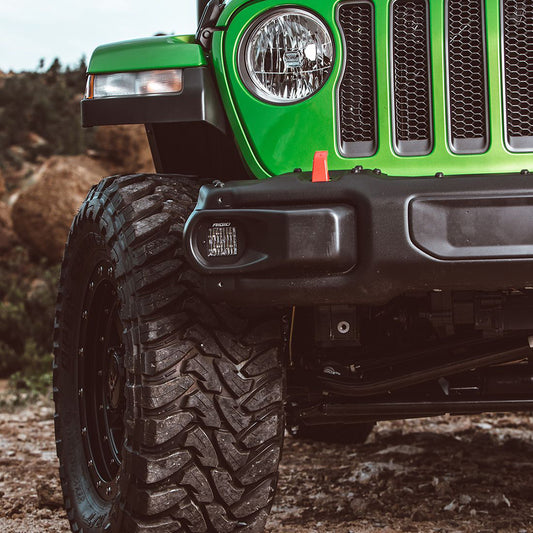 Green Jeep Wrangler with Rigid LED light, off-road tires, and custom front bumper for rugged terrain